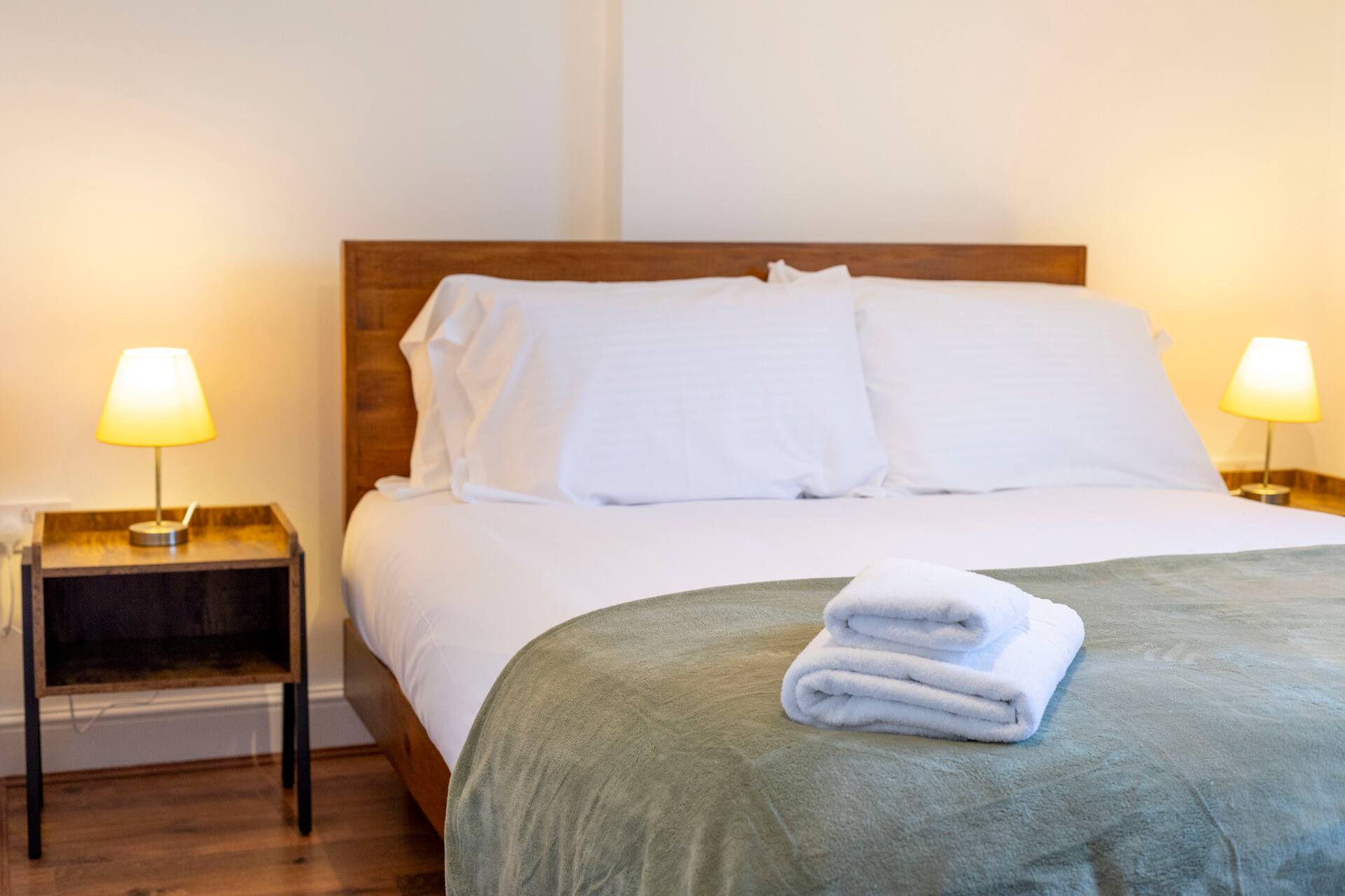 Cosy bedroom with warm bedside lighting and fresh towels
