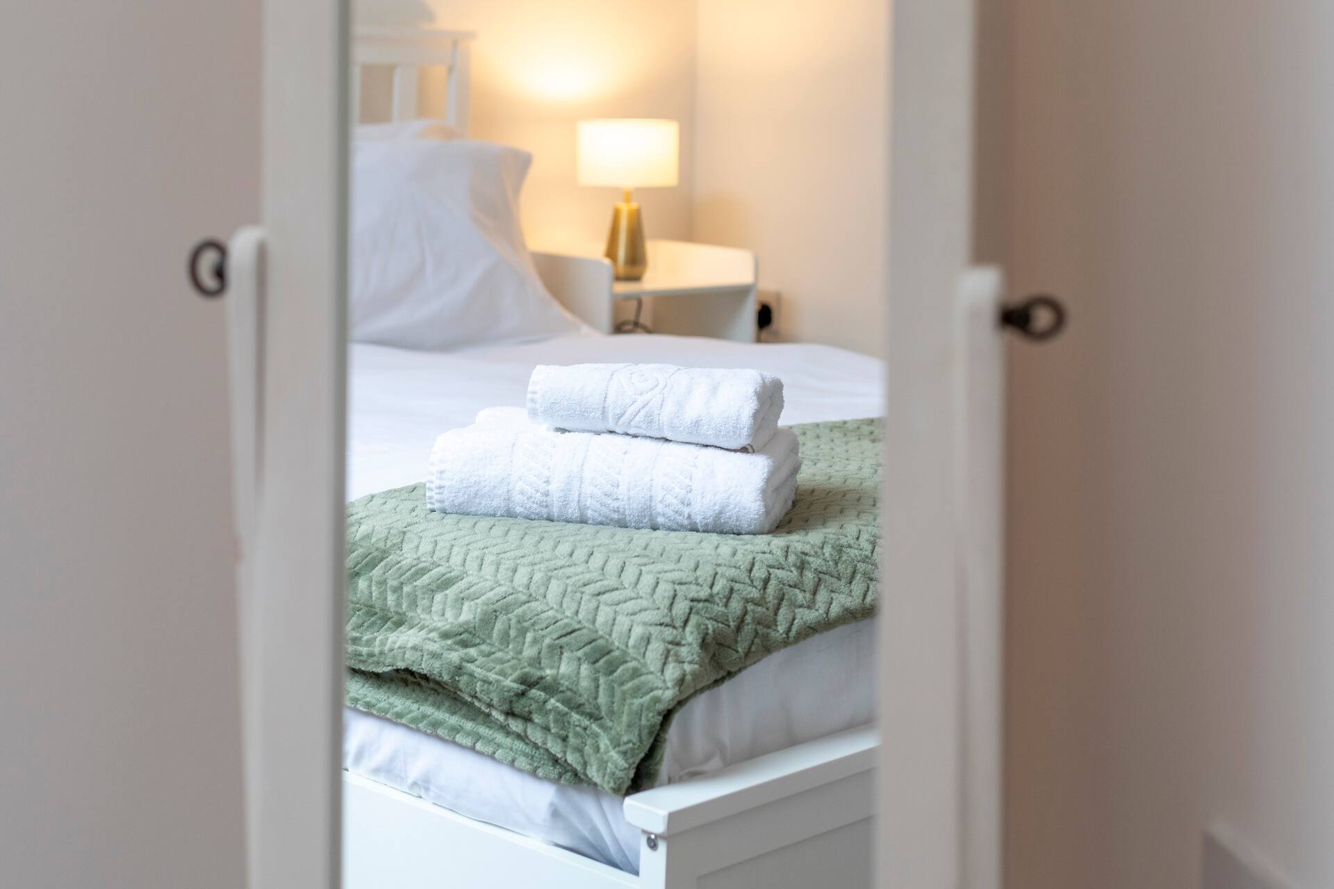 Artistic view of bedroom through doorway with fresh linens